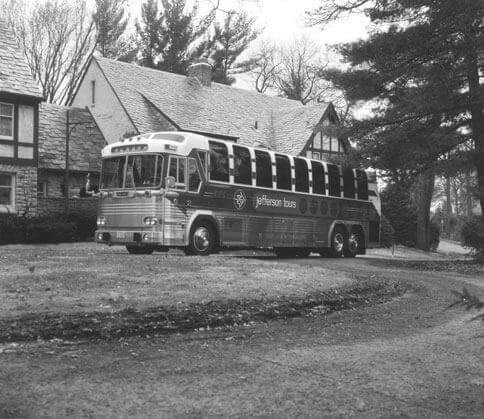 A Jefferson Lines bus from the 1960s parked in front of a home