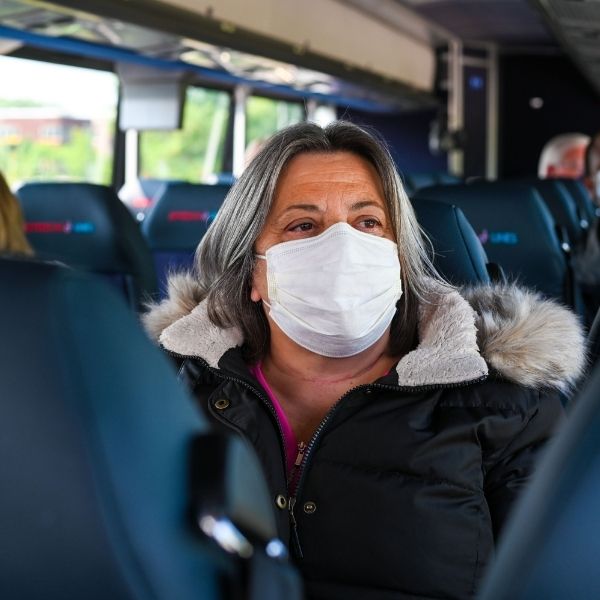 A woman wears her mask on the inside of the bus