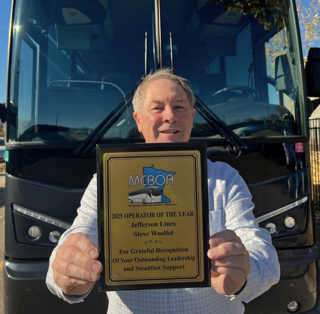 Steve Woelfel, CEO of Jefferson Lines, holds the Operator of the Year award in front of a Jefferson Lines charter bus.