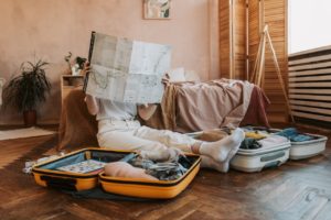 Woman sitting in front of suitcase looking at travel map.